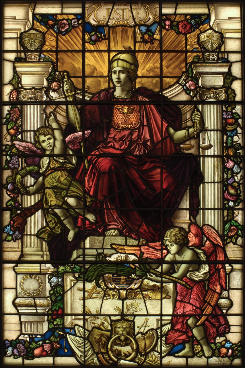 Stained glass window from the Baltic Exchange building, known as one of the Virtue windows. This was the central window in the war memorial at the Baltic Exchange. In Justice's right hand she holds a sword, which signifies the right of the law to exact punishment for offences, and in her left, scales which symbolize the impartiality with which justice is administered.