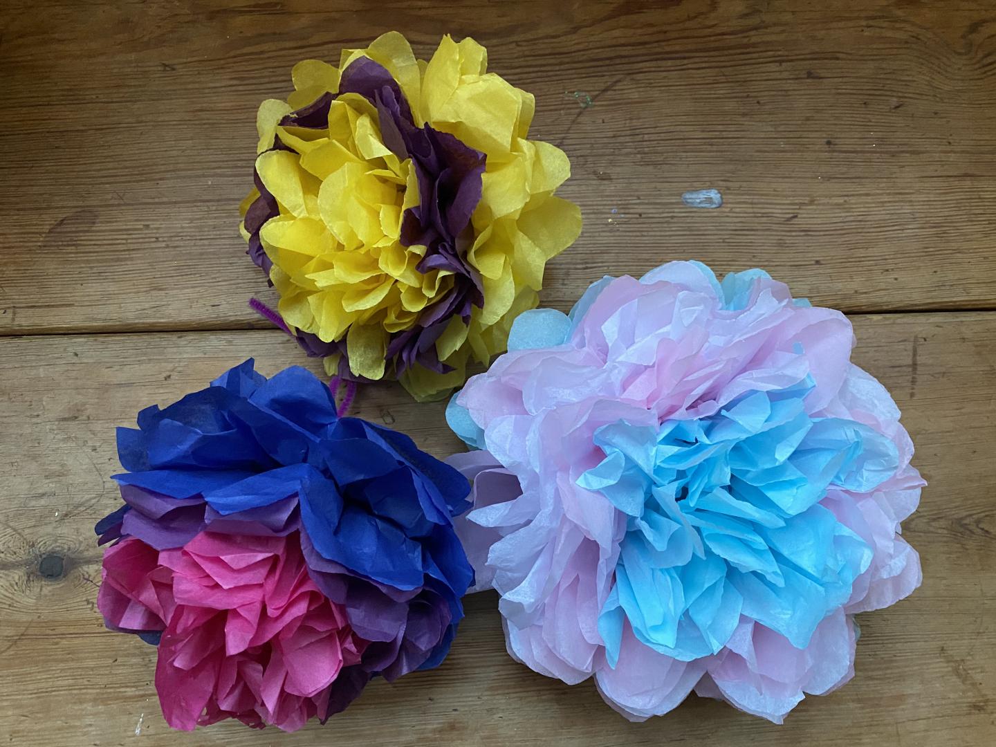 Three multicoloured pom poms on a table