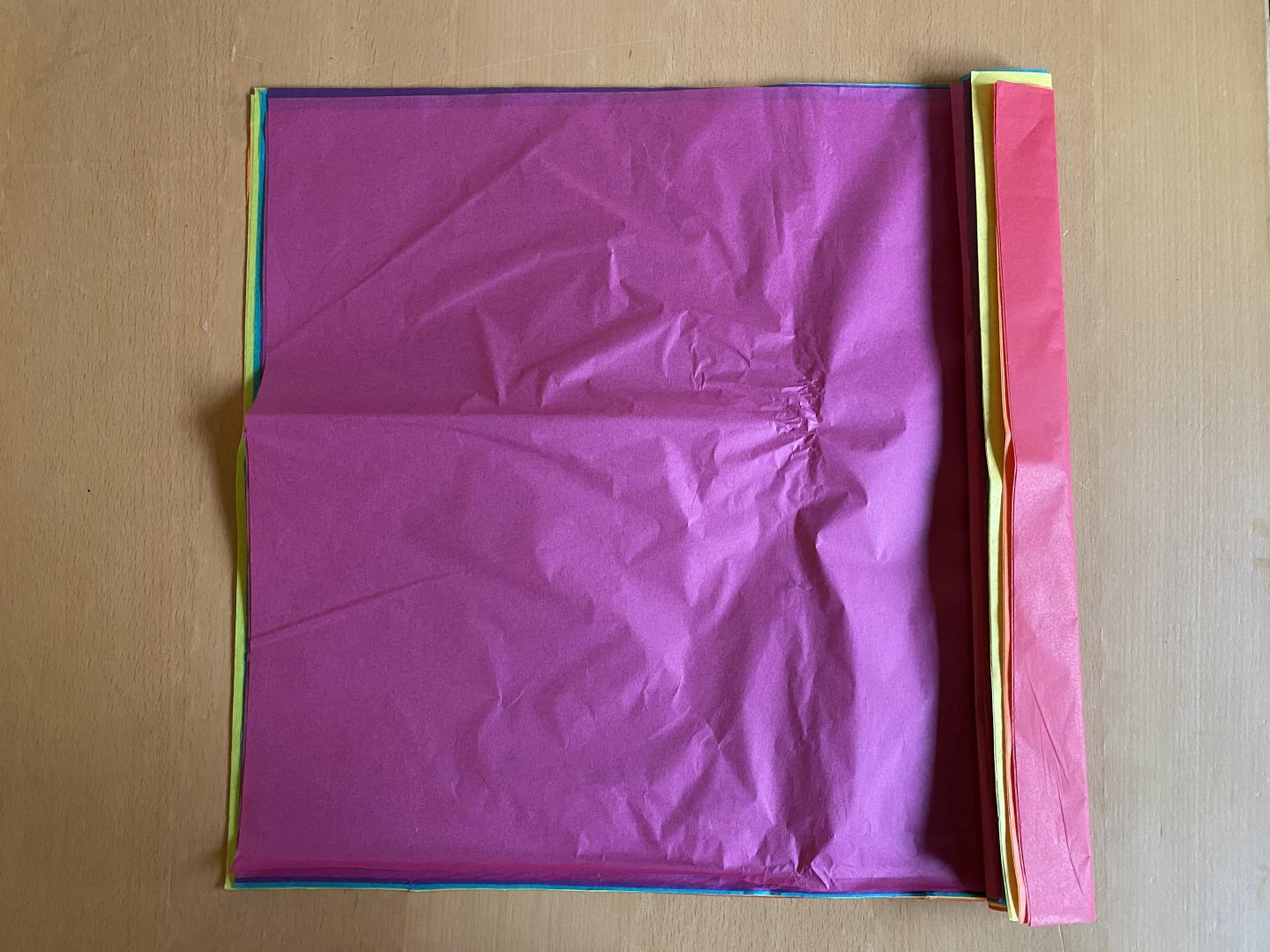 Coloured tissue paper stacked on top of each other folder over at the top