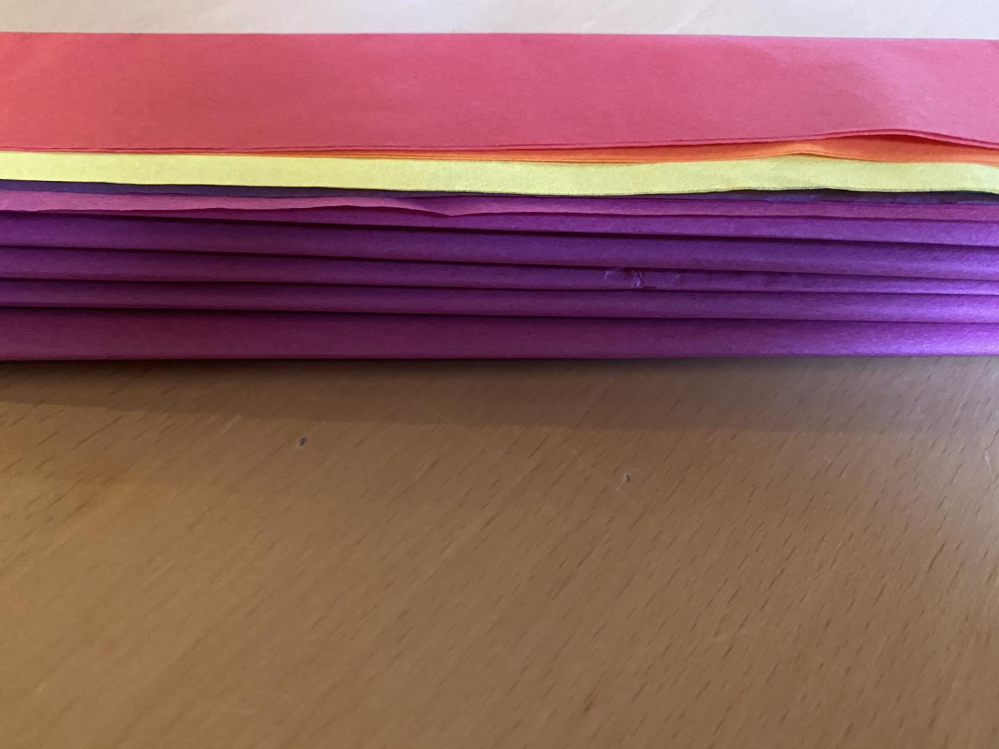 Close up of concertina folded stack of tissue papers with a strip of tissue at the end
