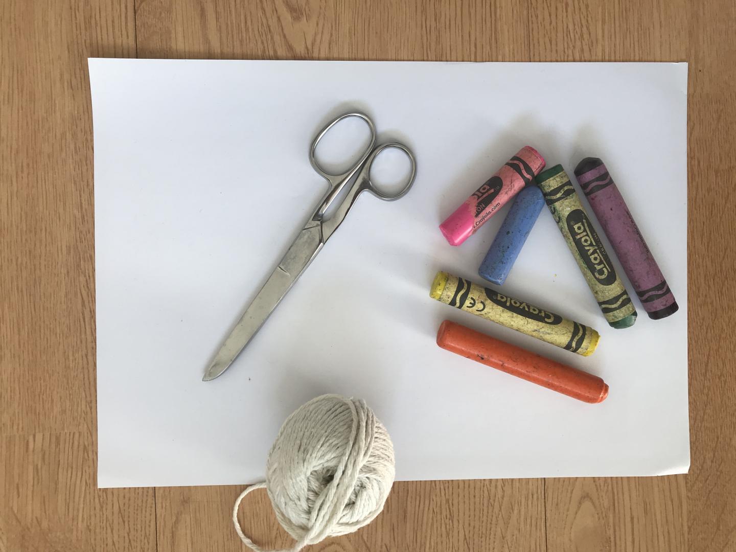 A piece of card, a pair of scissors, string and crayons. 