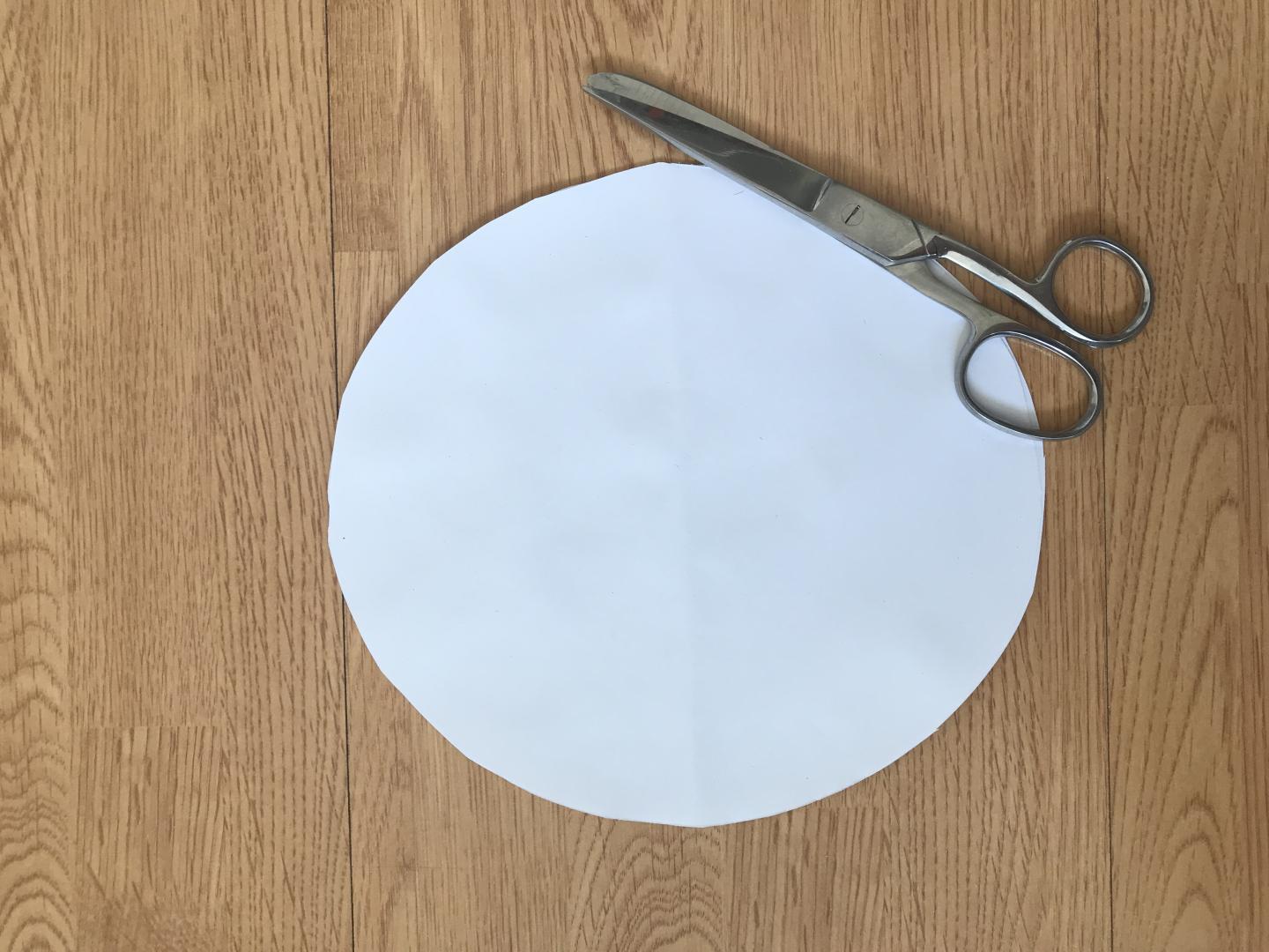 A circle cut from card with a pair of scissors nearby.