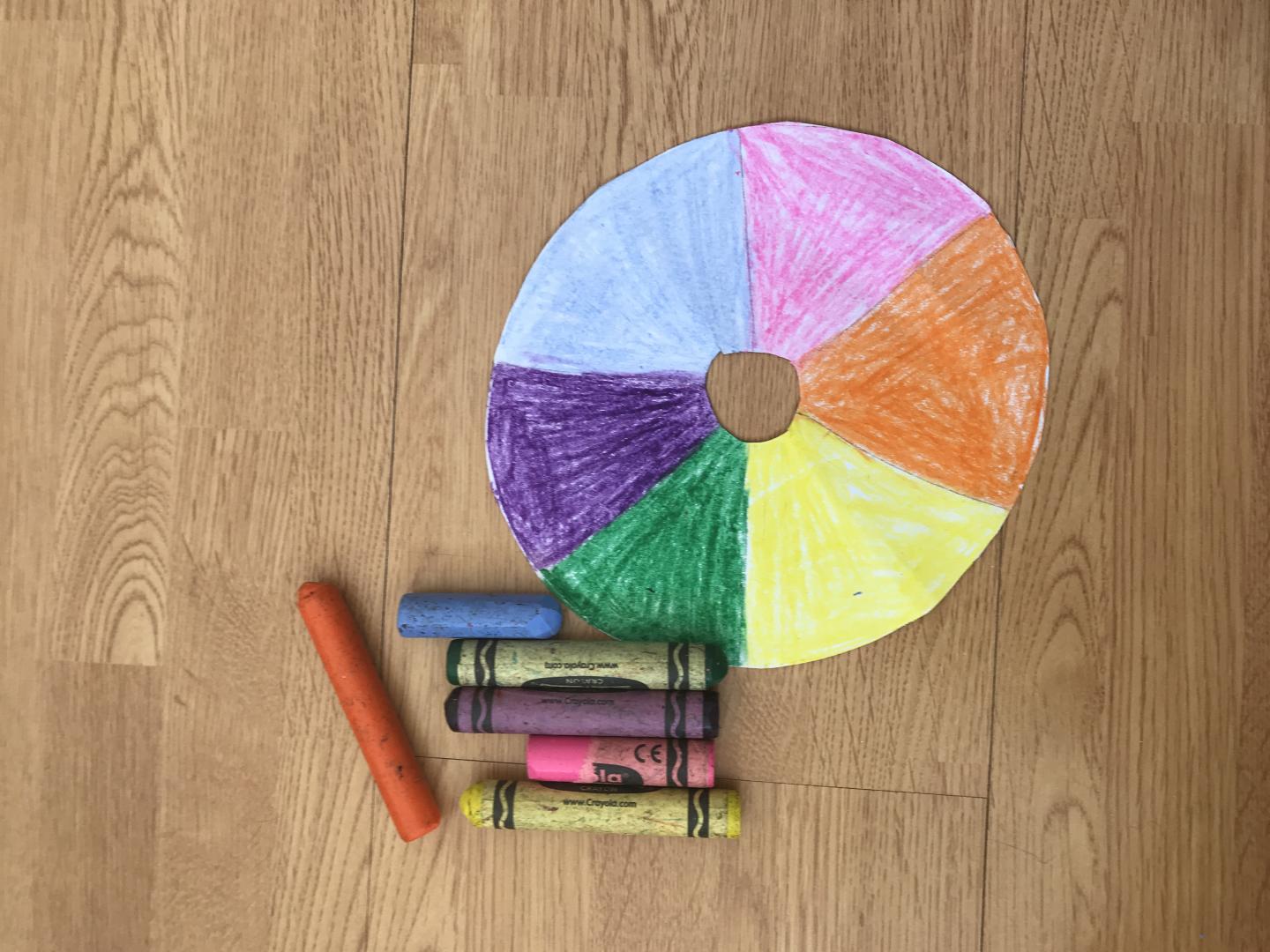 a doughnut shaped piece of card with 6 sections coloured in using blue, pink, orange, yellow, green and purple. 