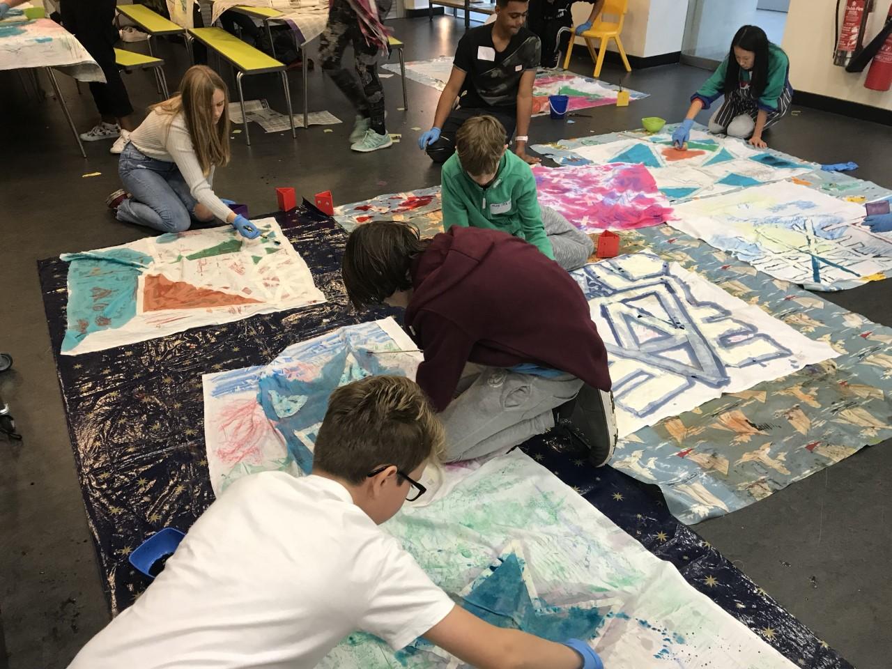 A group of young people on the floor painting onto fabric