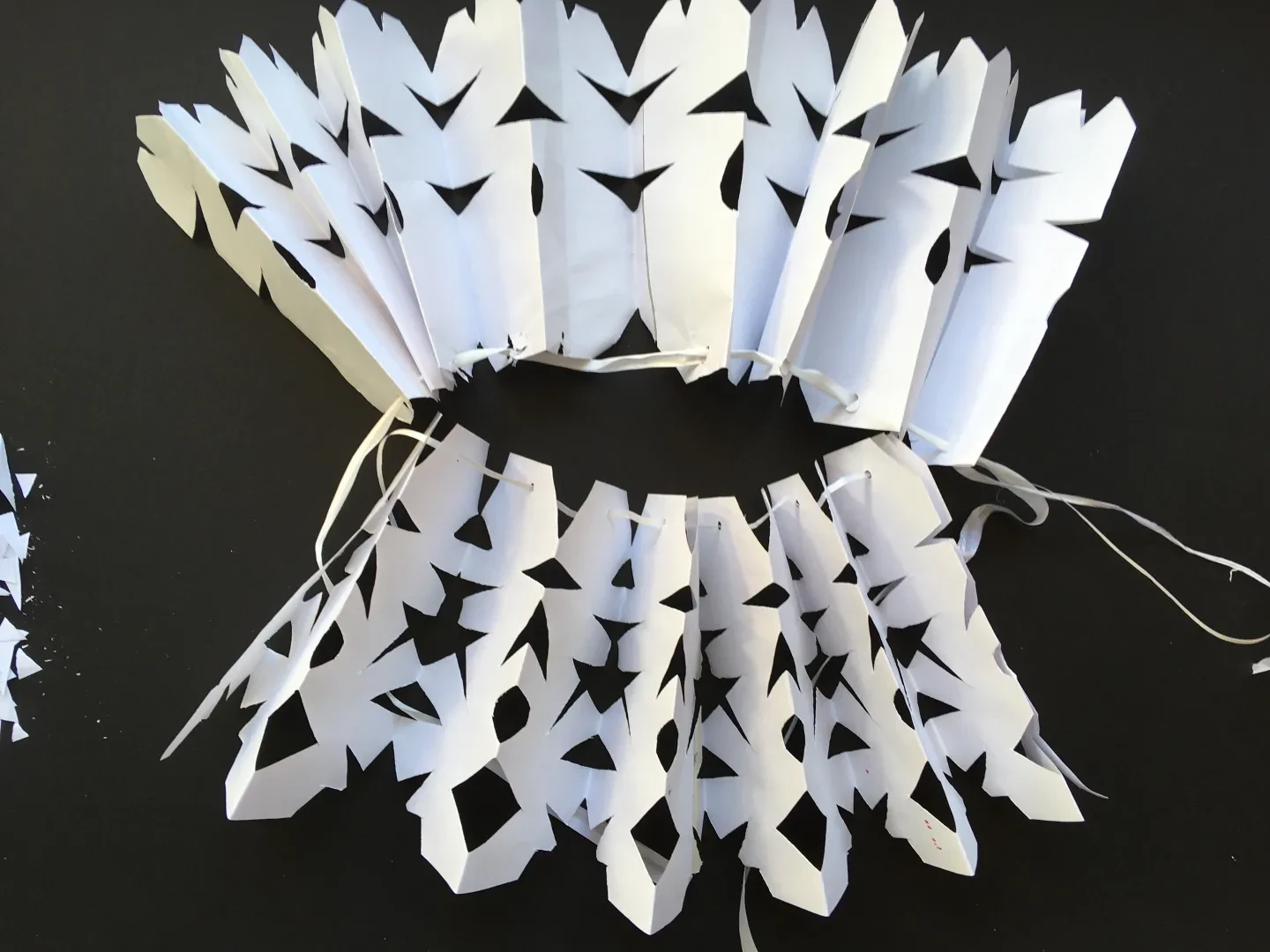 A ruff created out of paper with patterns cut into it. 