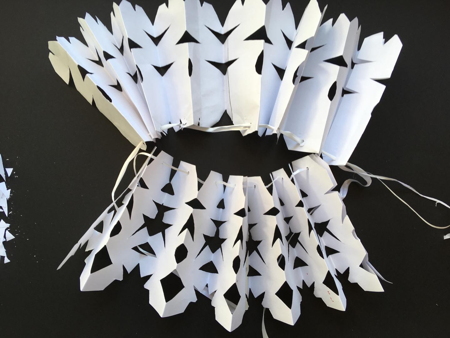 A ruff created out of paper with patterns cut into it. 