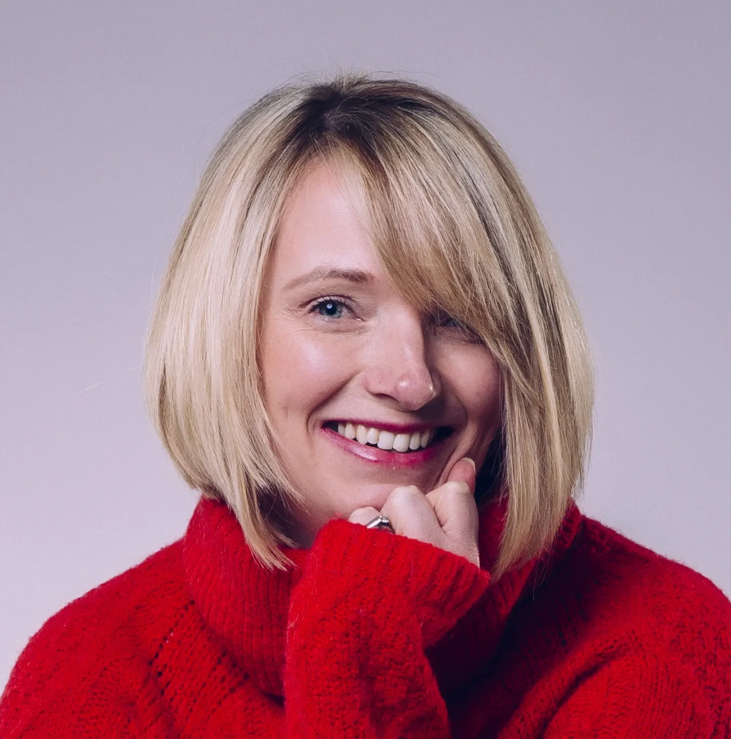 A photograph of Helen Dodd. Helen is a white woman with blonde, shoulder-length hair. She wears a red jumper.