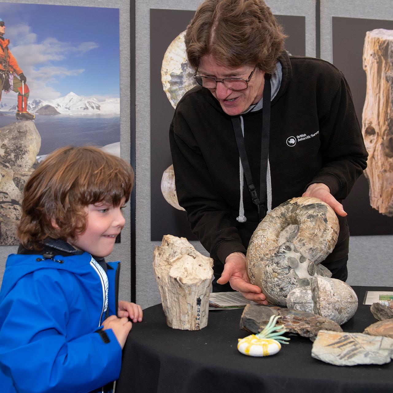 A young boy examines a fossil shown by a polar scientist as part of an event led by the British Antarctic Survey