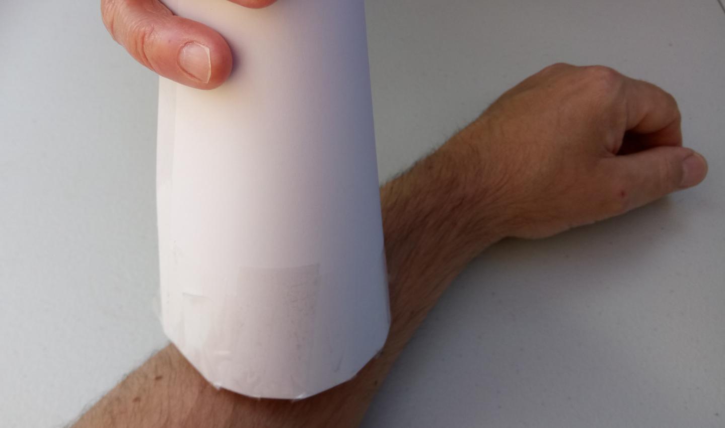 A paper megaphone being held against someone's arm.