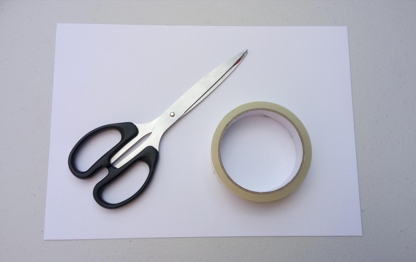A piece of white paper with a pair of scissors and a roll of tape.