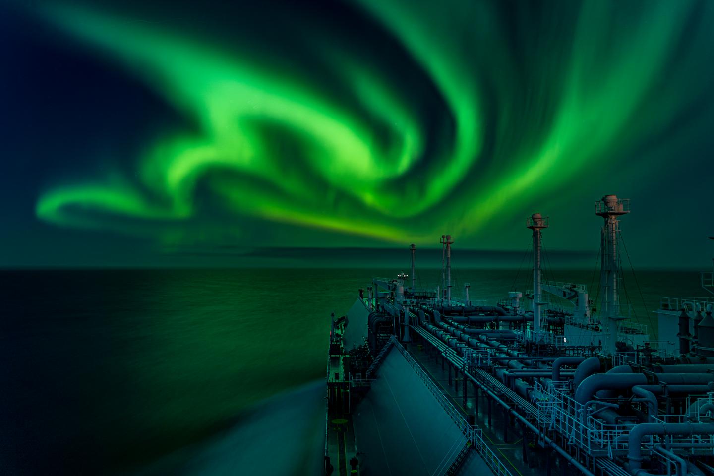 Green aurorae dance over the sea in front of a ship