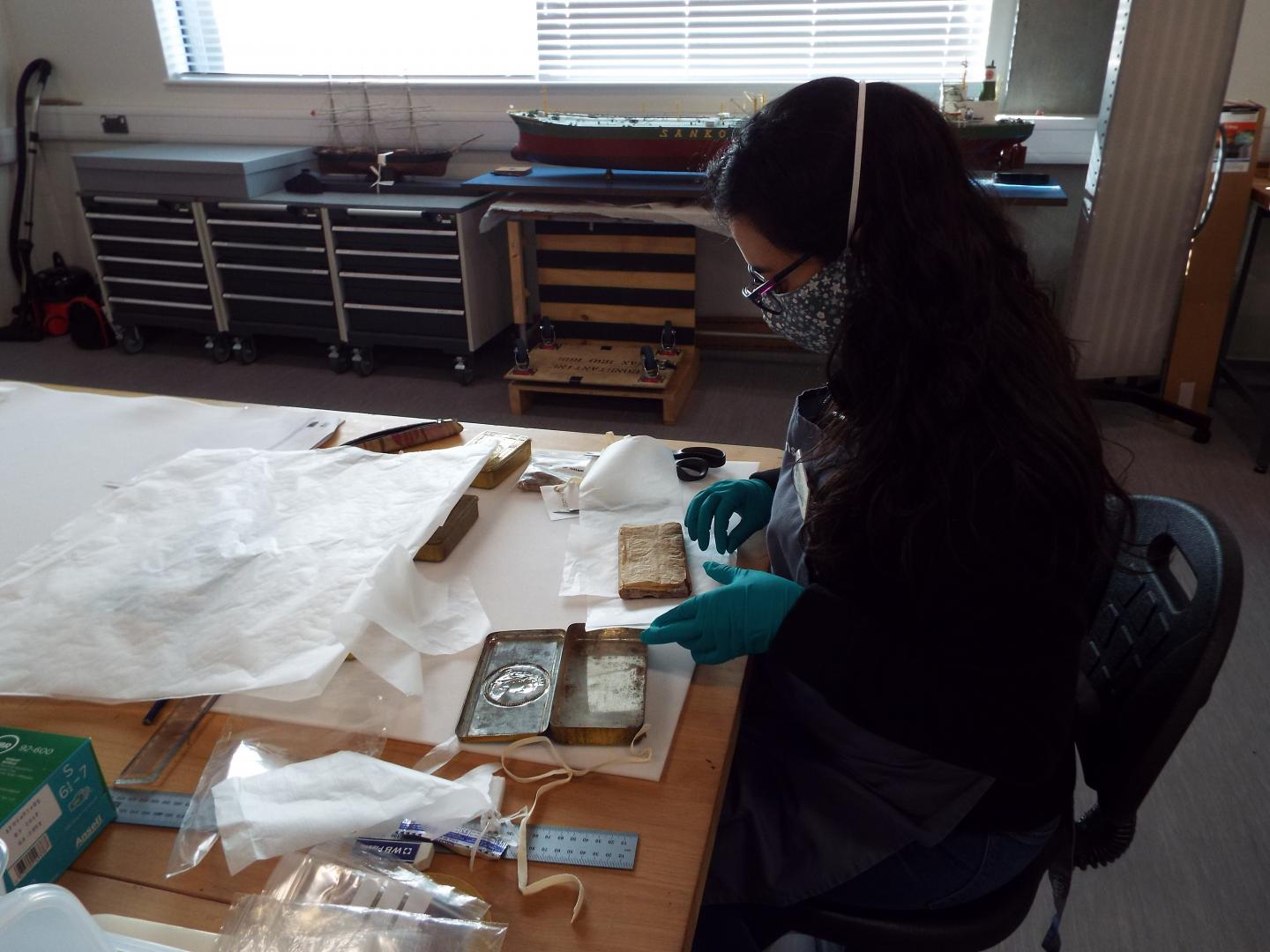 A conservationist carefully holds an old chocolate box