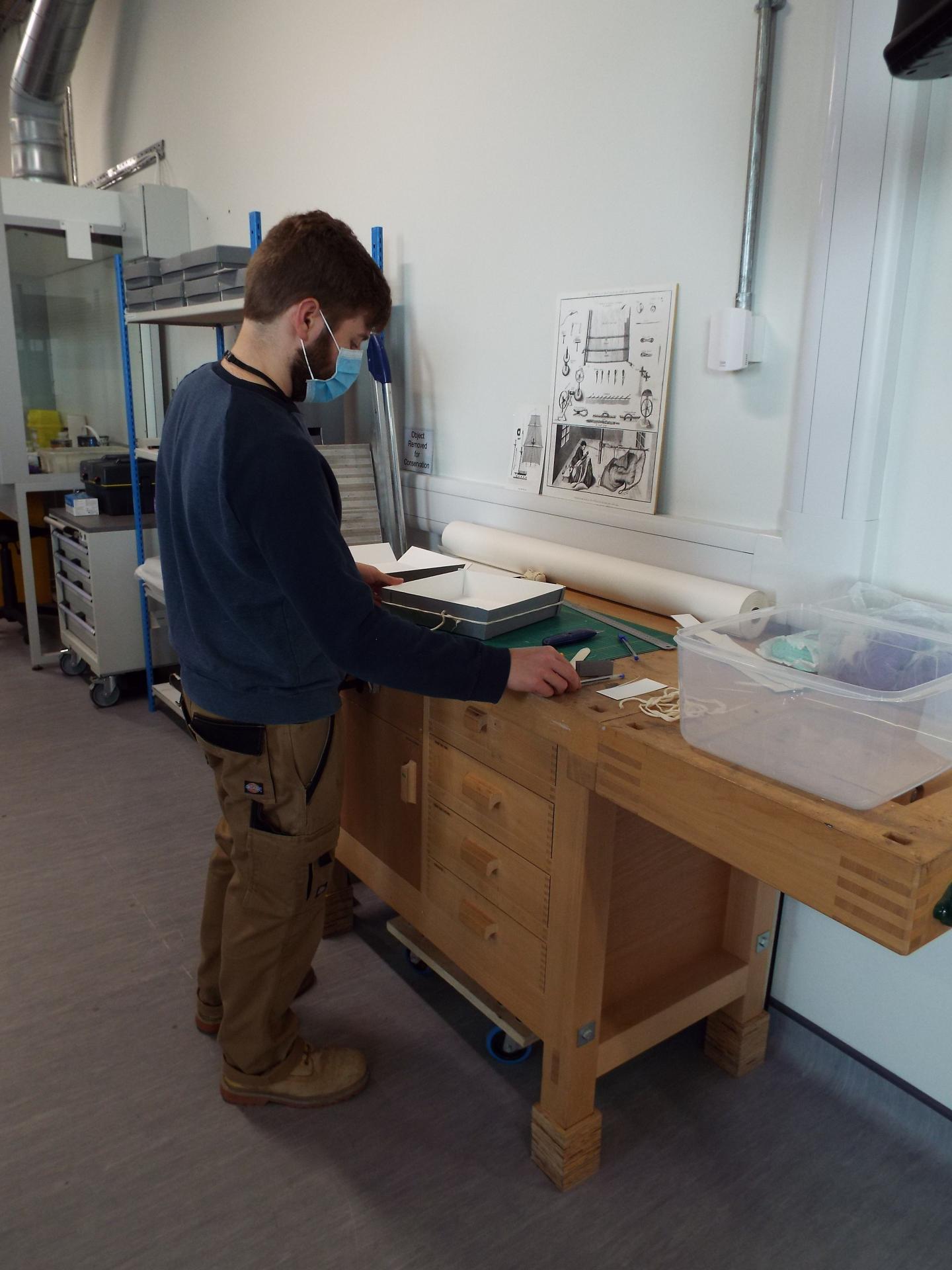 A conservationist stands at a desk creating trays