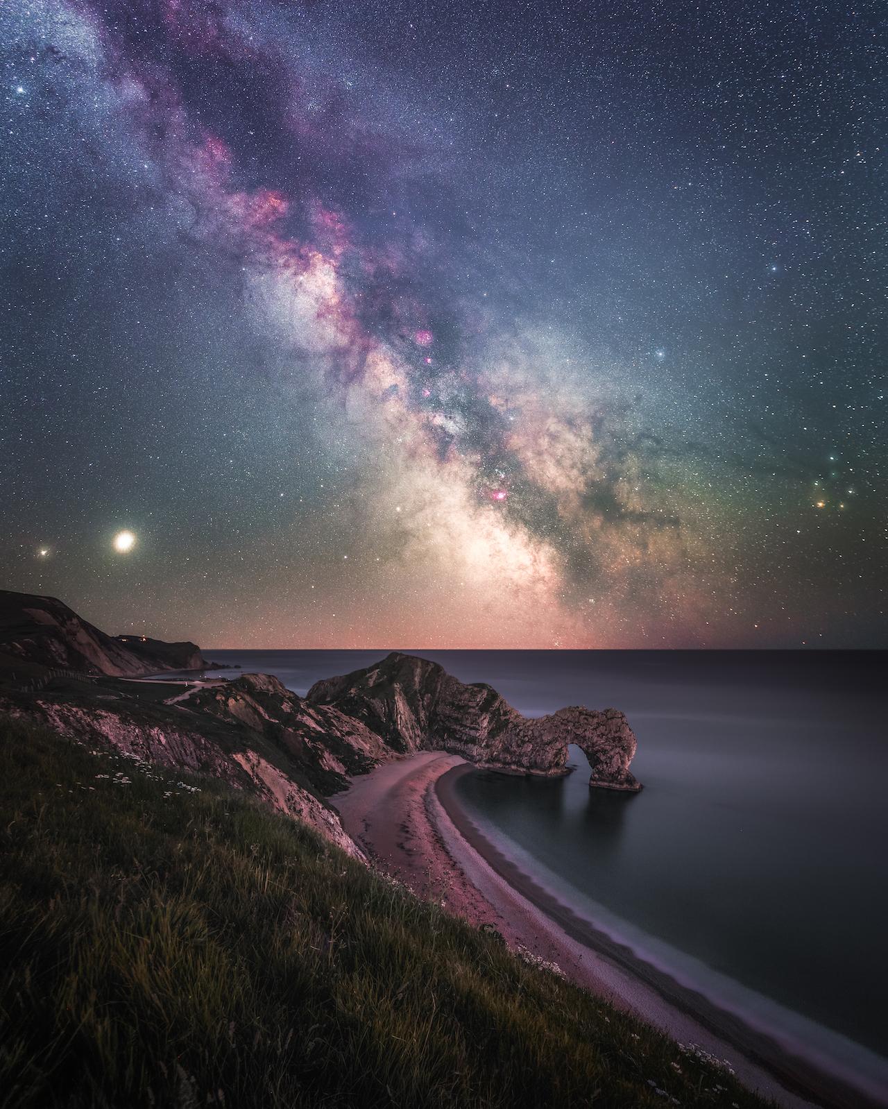 Stars in the Milky Way rising over the rock formation Durdle Door on the Jurassic Coast