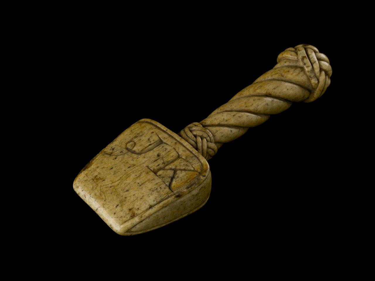 A wooden tool with initials carved on it