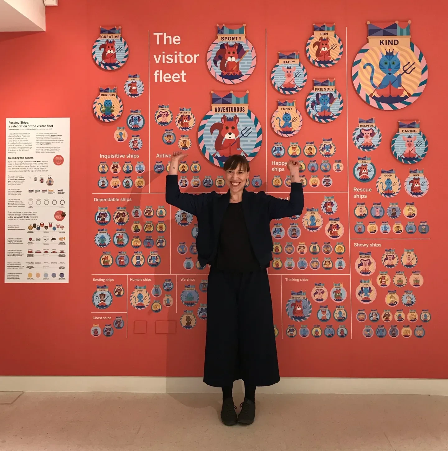 A woman stands in front of a wall of artwork inspired by ship's badges