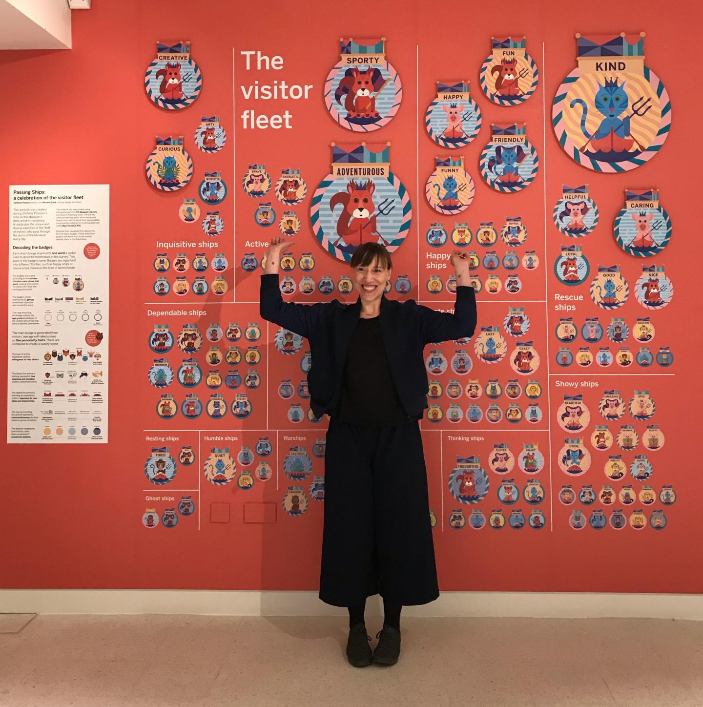 A woman stands in front of a wall of artwork inspired by ship's badges