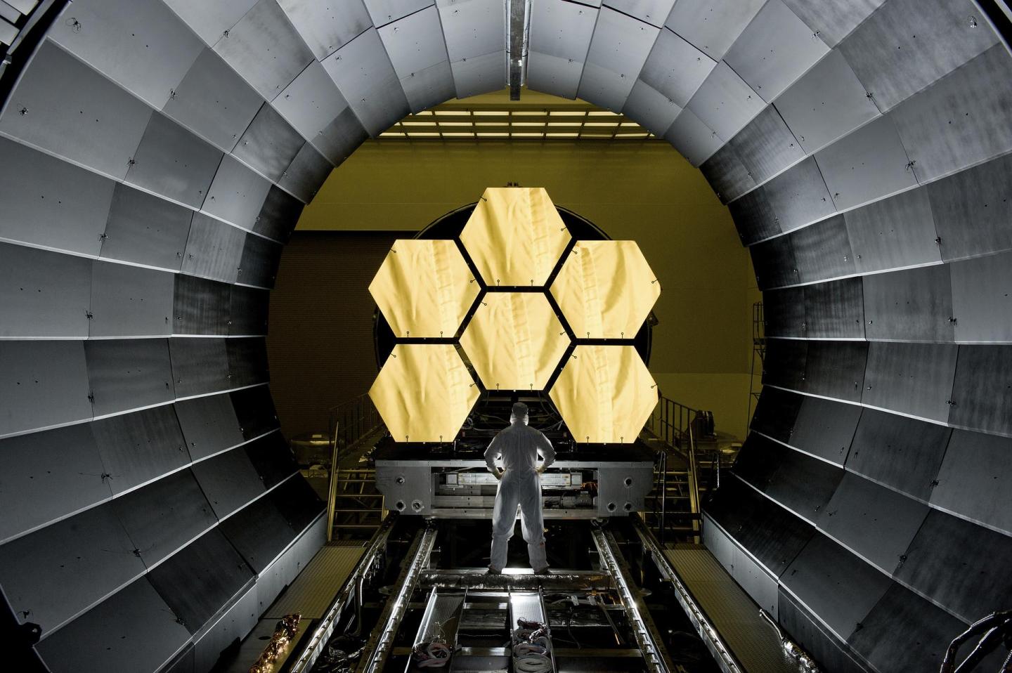 A scientist stands in front of the James Webb Space Telescope during testing