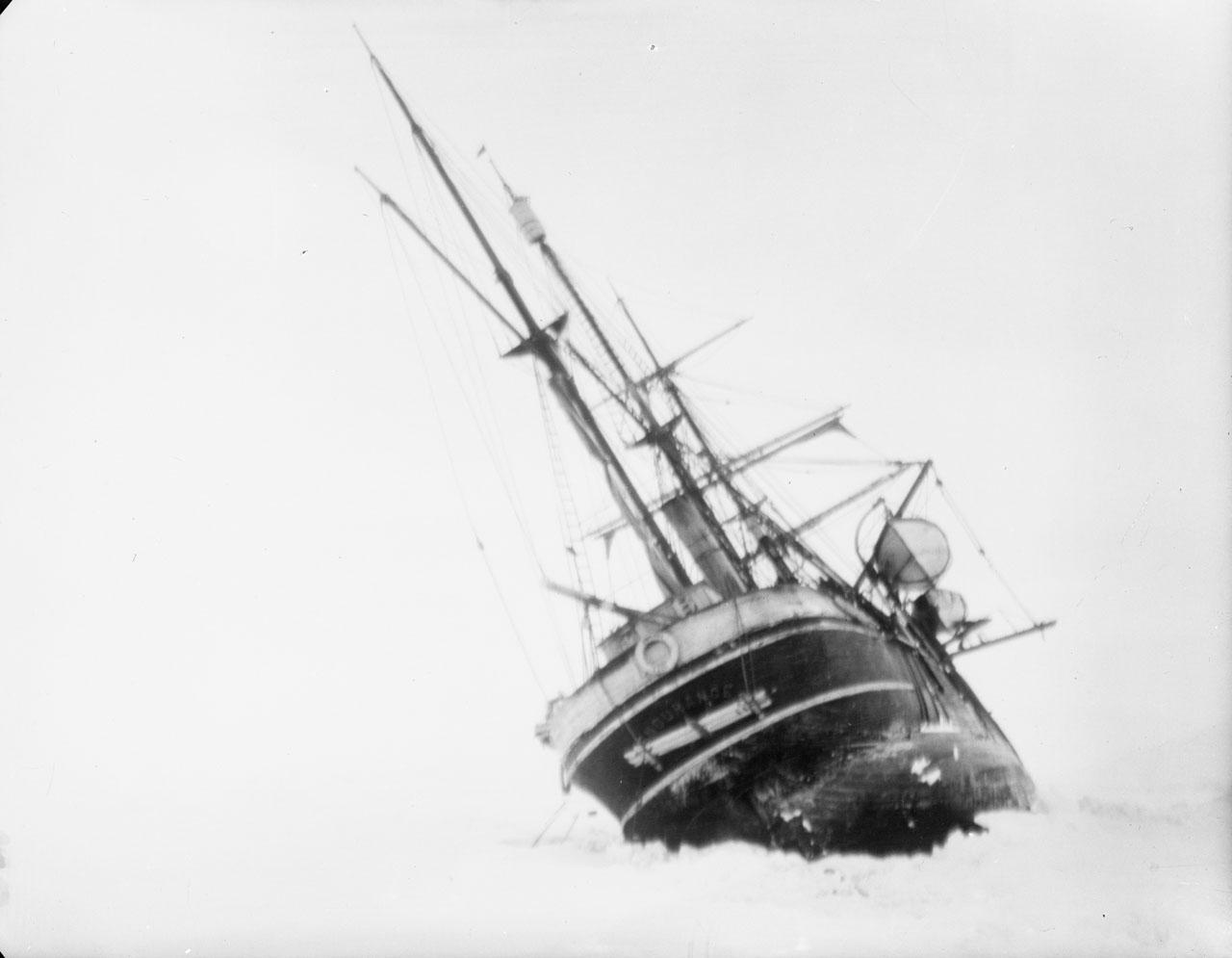 Historic black and white photograph showing Sir Ernest Shackleton's ship Endurance stuck in the ice, leaning to one side