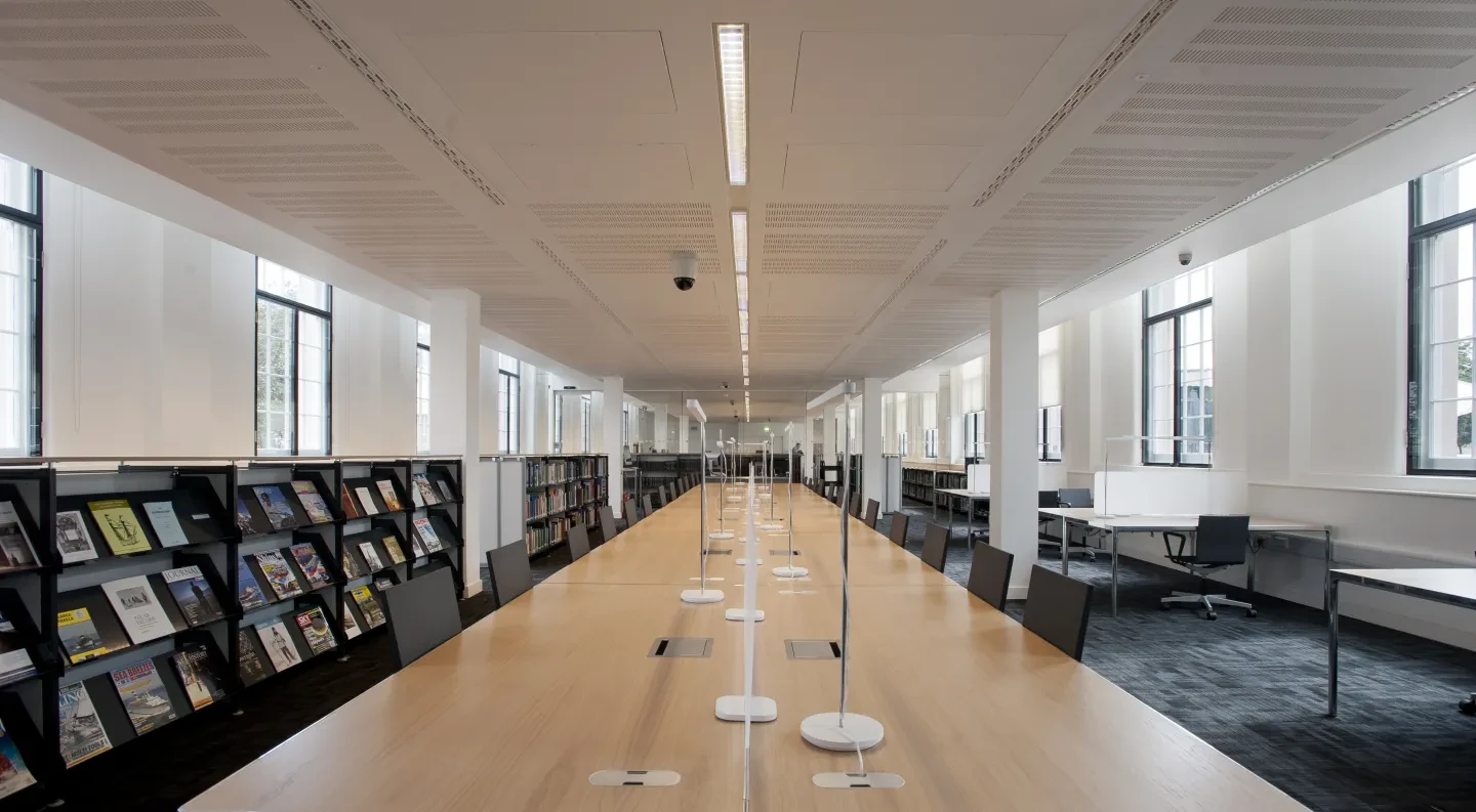 A long, modern desk, bookshelves and desks