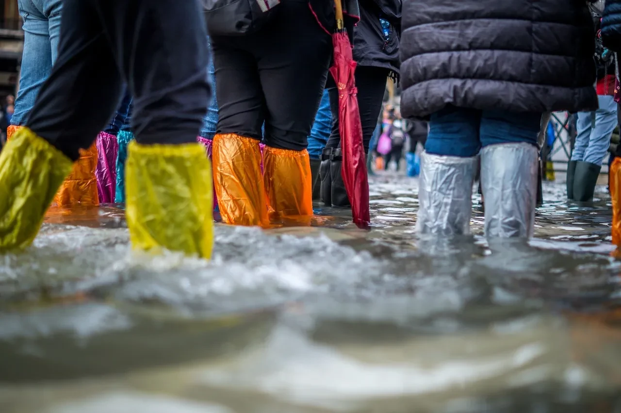 Tourists wearing plastic overshoes try to stay dry in a flooded square in Venice