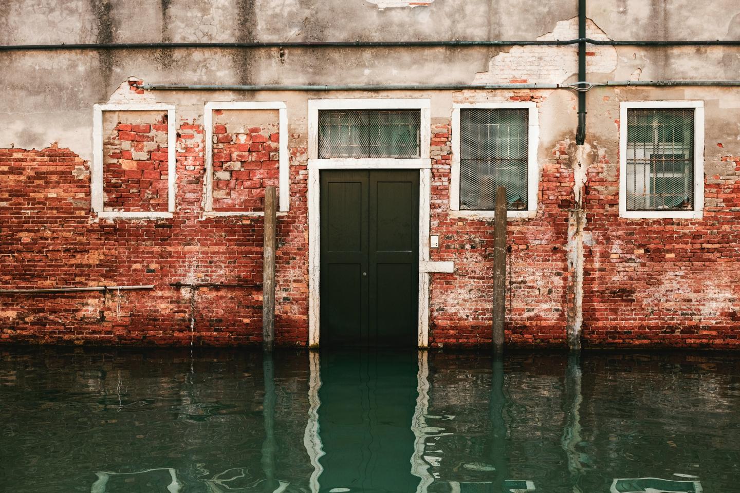 A wall in Venice partially submerged in water. The red bricks are looking damaged