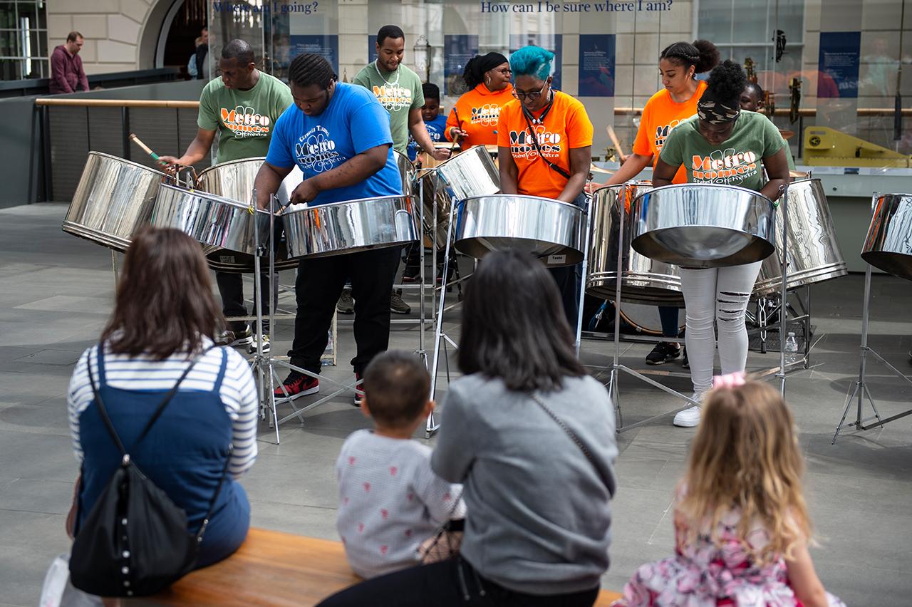 A steel band plays in the National Maritime Museum as families look on