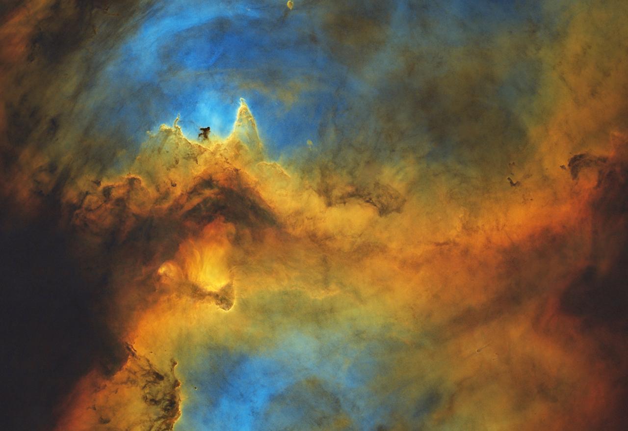 Image of a blue, yellow and orange nebula which resembles a dragon with a figure on its head