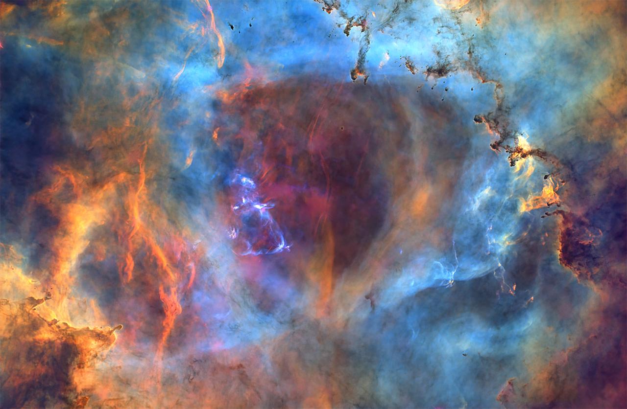 Image of core region of Nebula NGC 2244, lots of interacting clouds of gas in different colours including gold, purple, blue, green