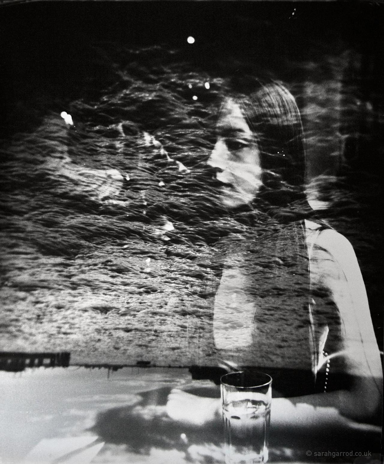 A black and white photograph showing a woman looking out, overlaid with a seascape