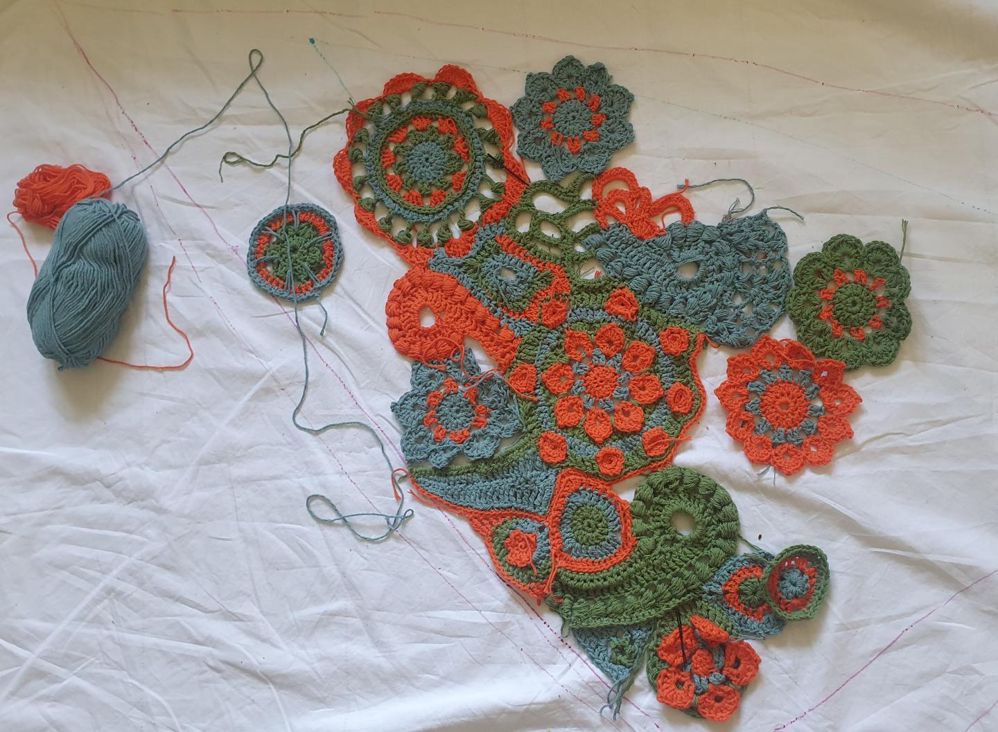 Work in progress image of blue, orange and green crochet flowers 