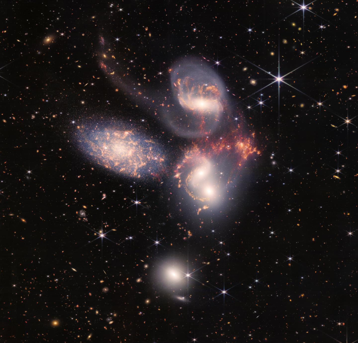 Image of a group of five galaxies that appear close to each other in the sky: two in the middle, one toward the top, one to the upper left, and one toward the bottom. Four of the five appear to be touching. One is somewhat separated.