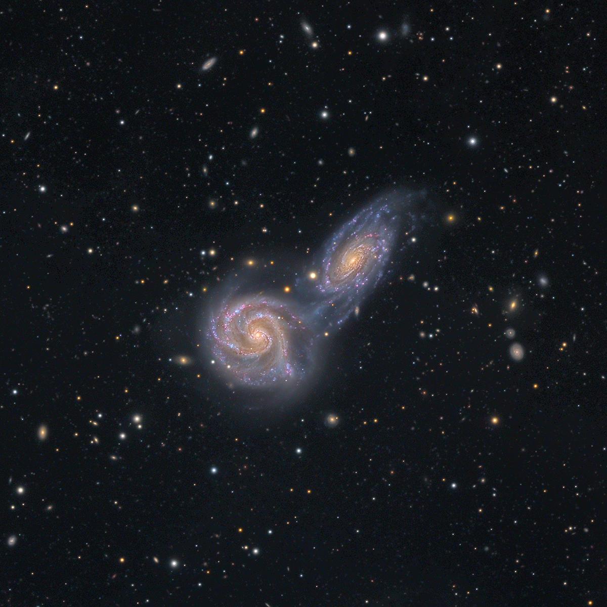 Two galaxies seemingly colliding, against a starry black sky 