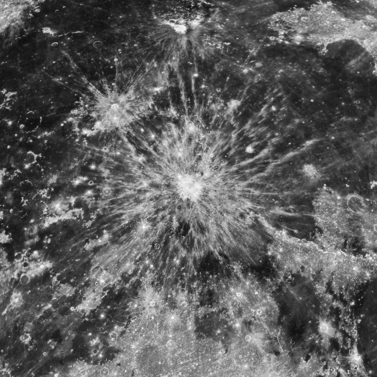A black and white photo of the Moon's surface, focusing on a star-shaped meteor crater