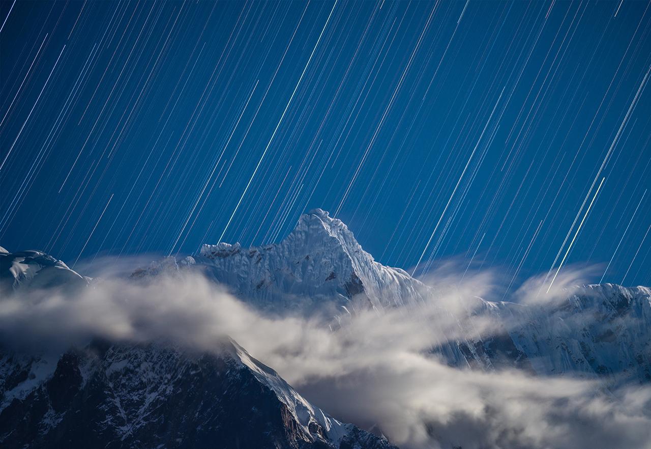 Shooting stars rain down over a snow capped mountain