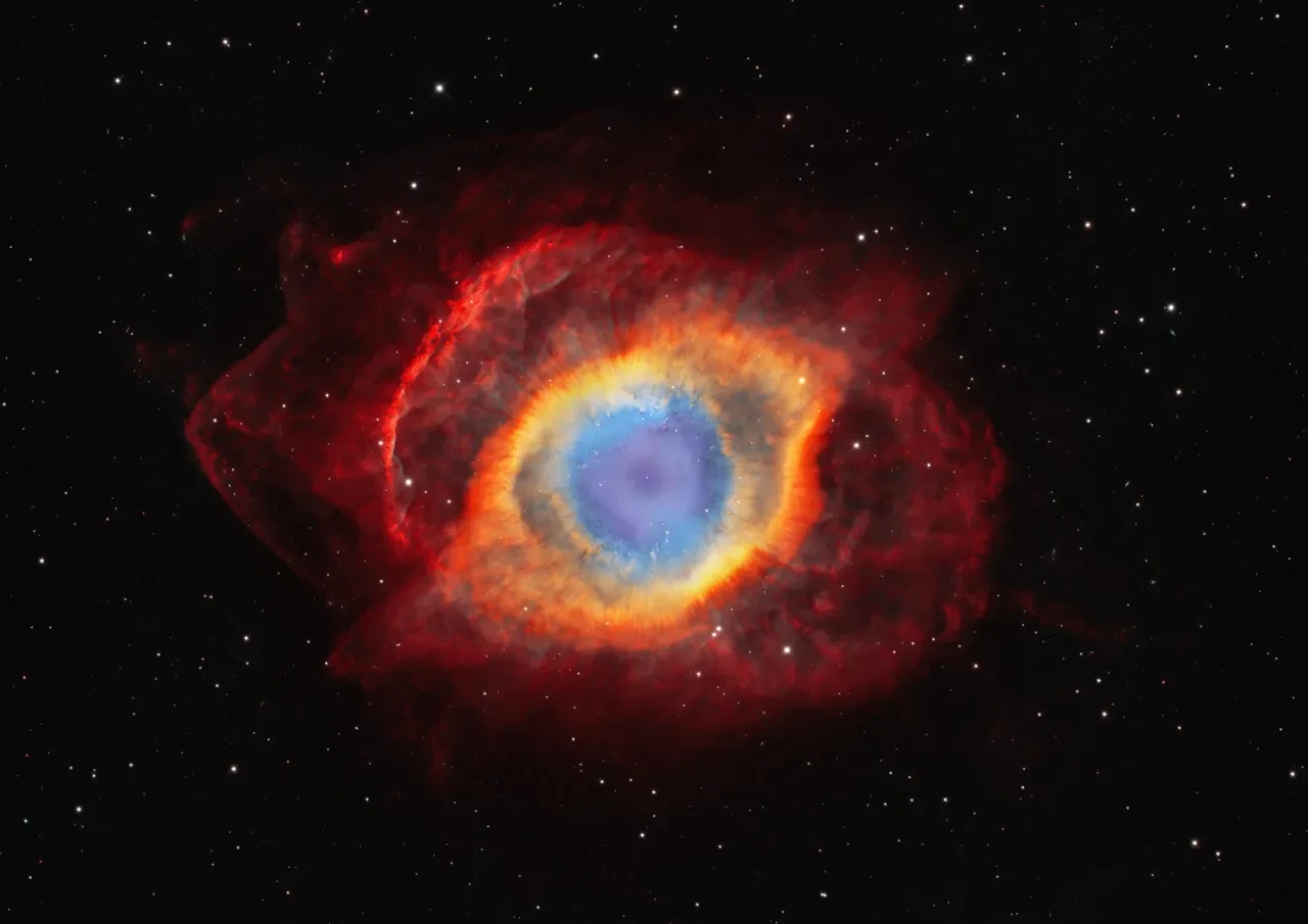 Nebula which resembles an eye, with blue in the centre, then a yellow layer, then a deep red layer on the outside