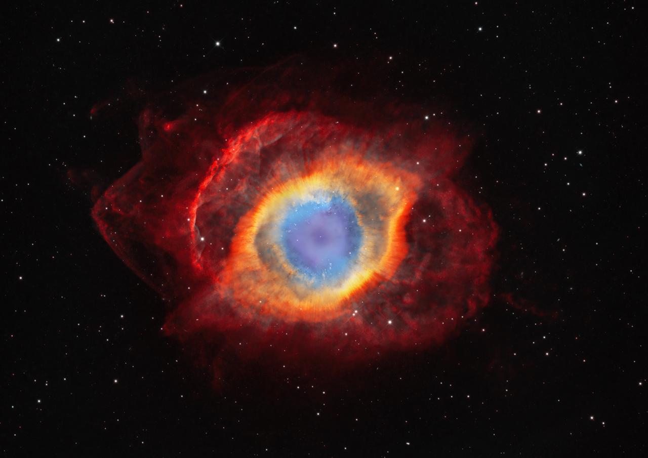 Nebula which resembles an eye, with blue in the centre, then a yellow layer, then a deep red layer on the outside