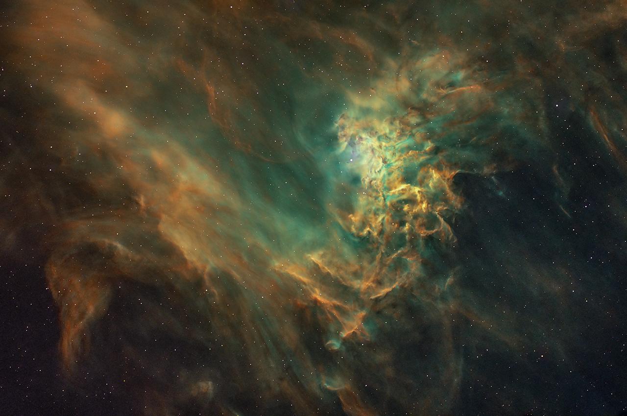 Landscape image of a gold and teal nebula, with more solid clouds at the centre in gold