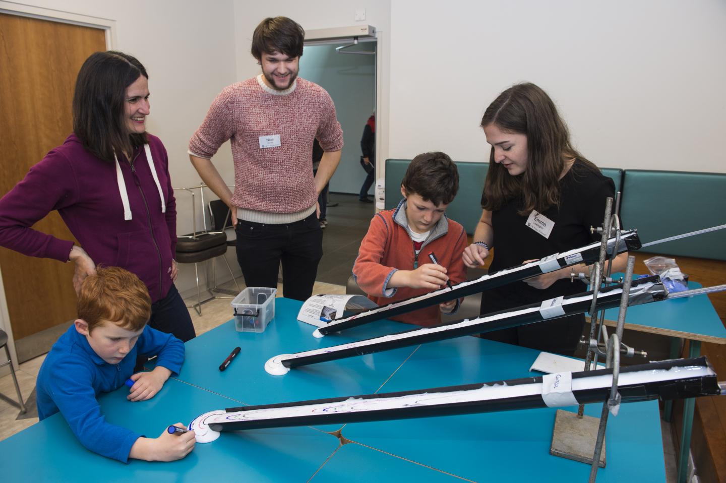 A group of adults and children watch a science experiment about glacier movement.