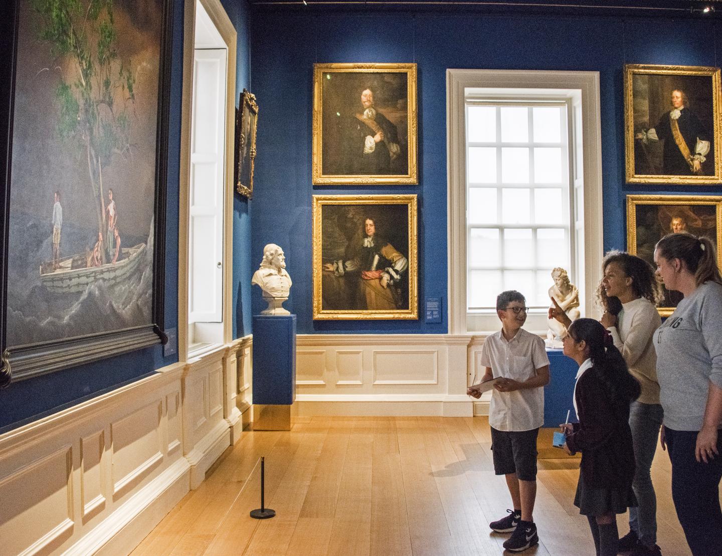 A group of children and adults look at a painting in the Queen's House