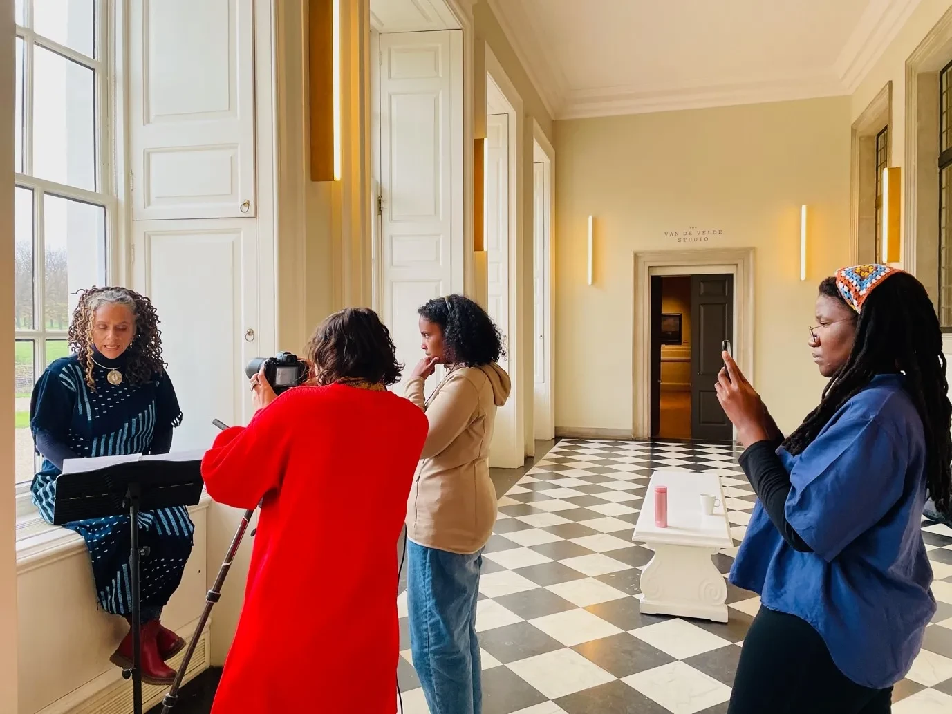 Three women film makers filming a performer sitting on a window ledge in the Queen's House