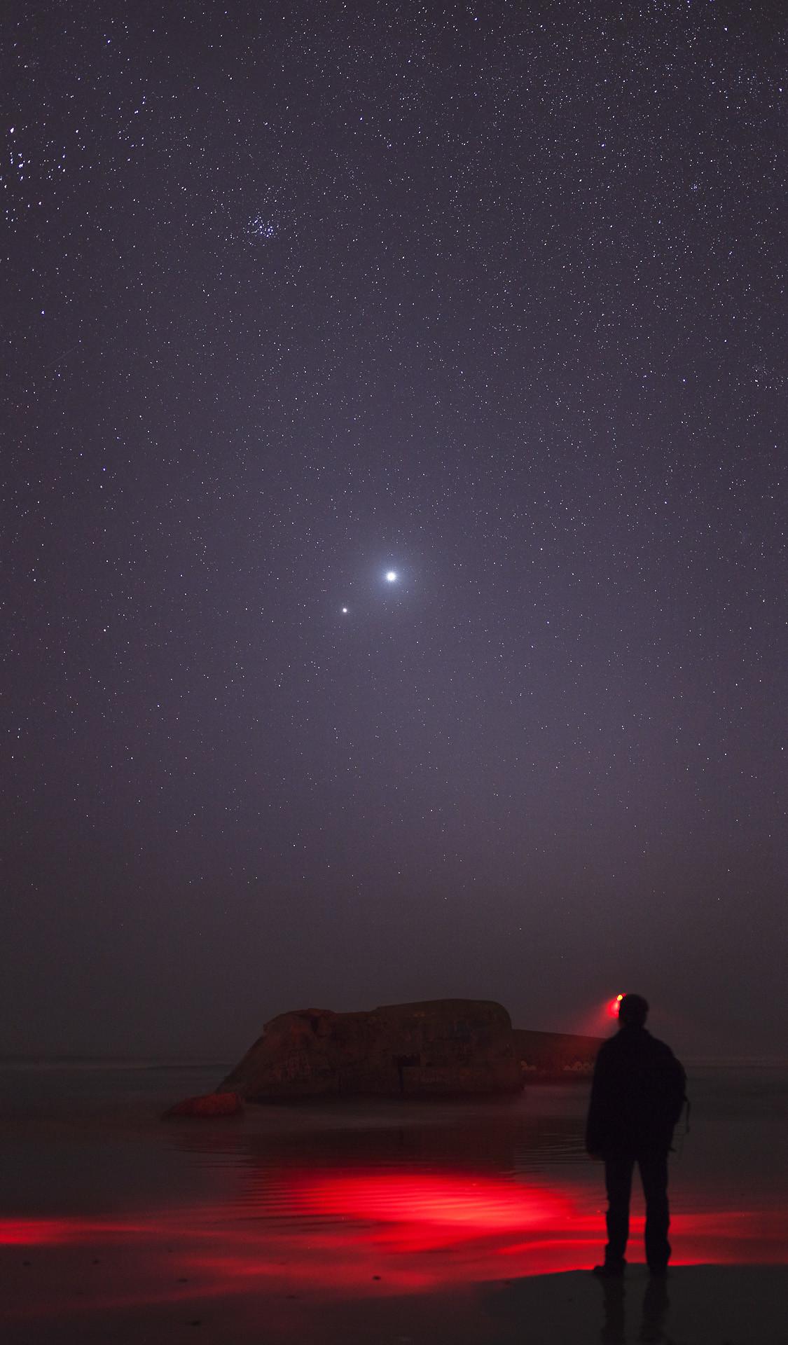 Image of man standing looking at night sky, which has two bright lights close together which are Venus and Jupiter