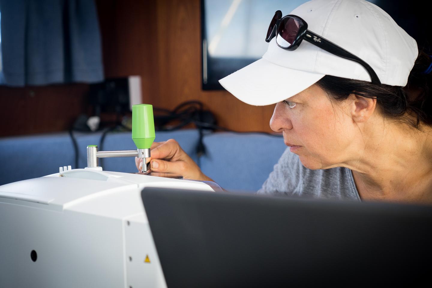 A scientist studies a plastic sample through a microscope