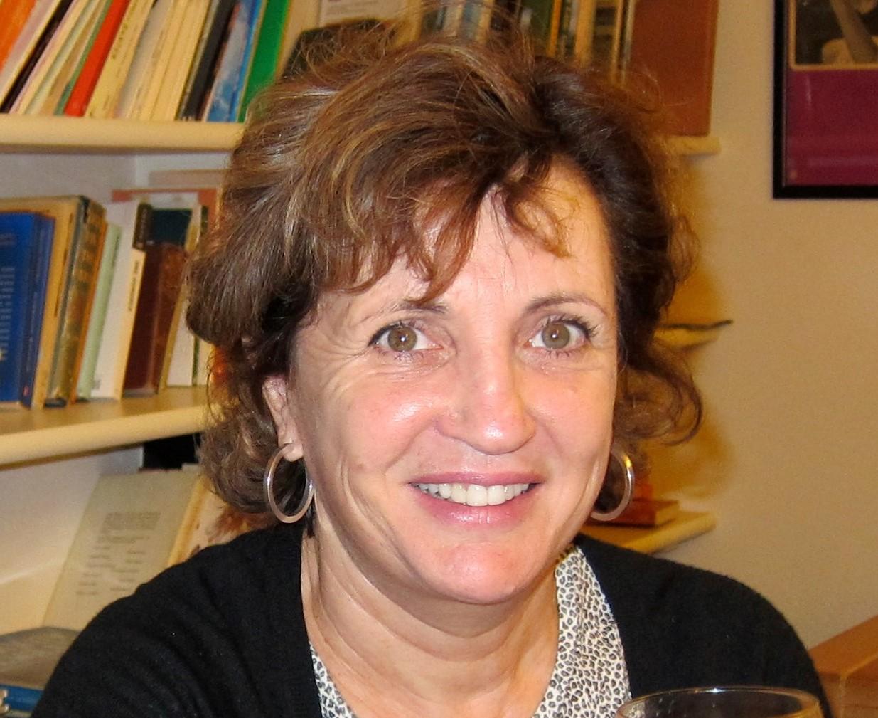 Colour Photo headshot of a white woman smiling against a book case