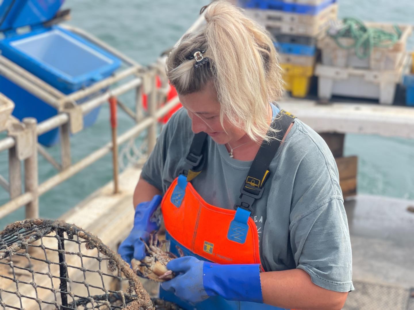 Ashley Mullenger on fishing boat holding a crab
