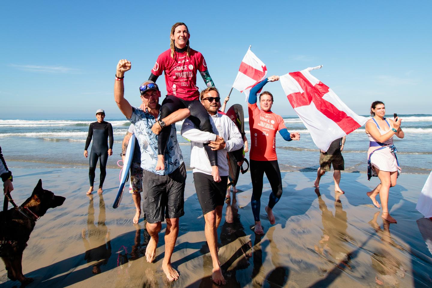 Melissa Reid being held aloft by surfers after winning ISA World Para Surfing Championship