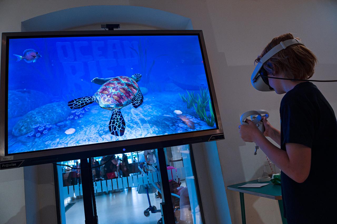 A boy plays with a VR headset showing a turtle's journey during World Oceans Day at the National Maritime Museum