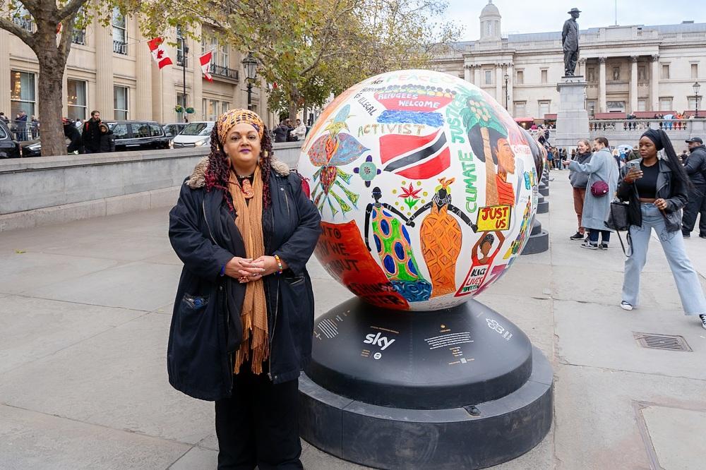 Portrait of Zita Holbourne beside her artistic globe