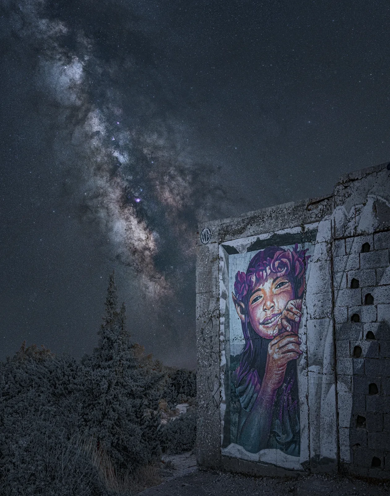 Image of graffiti of girl on wall with the Milky Way diagonal in the sky behind