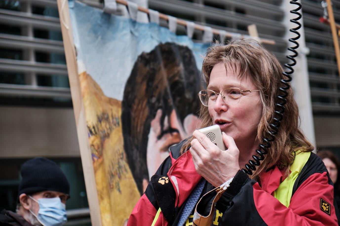 A women speaking into a megaphone with back drop behind